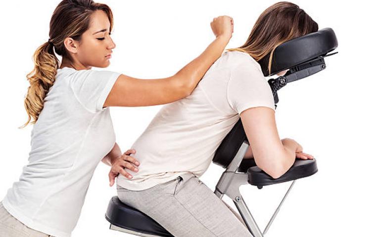 Person relaxing in massage chair as professional LMT gives relaxing massage